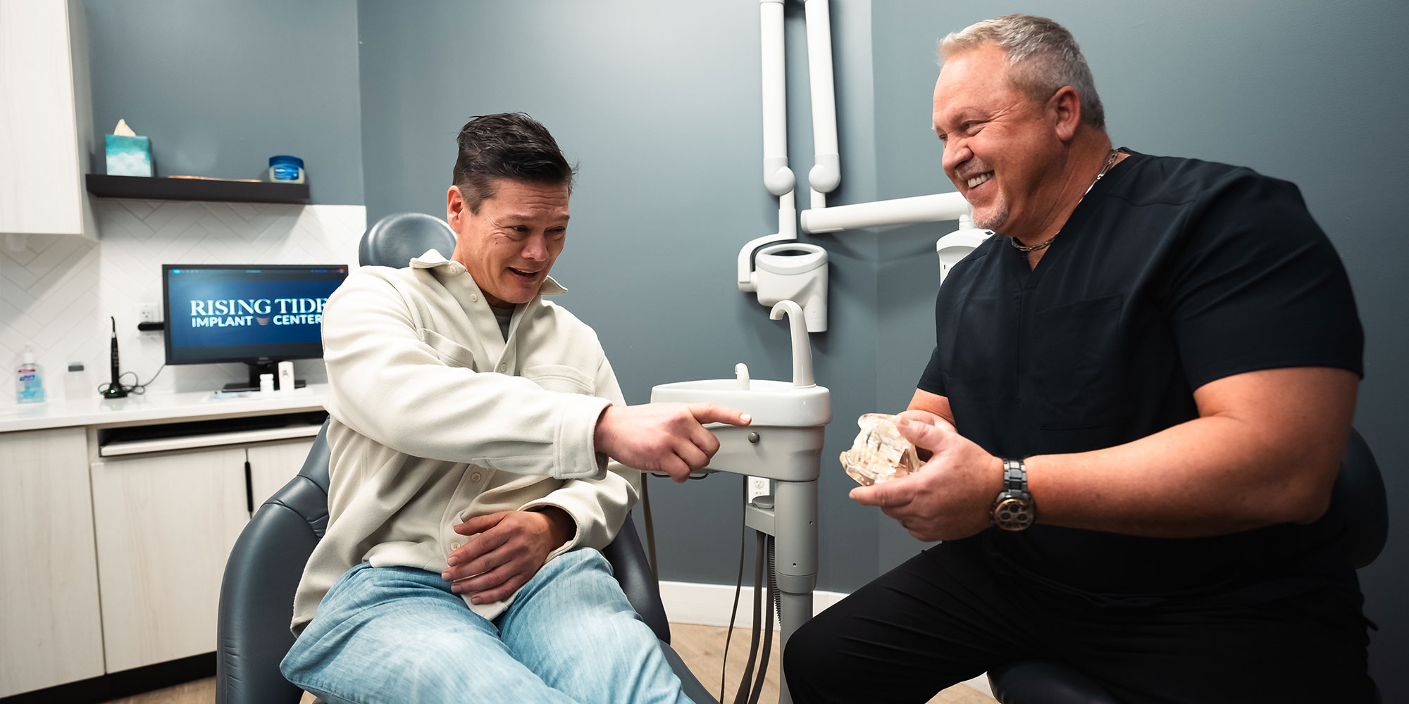 patient pointing to model of dental implants