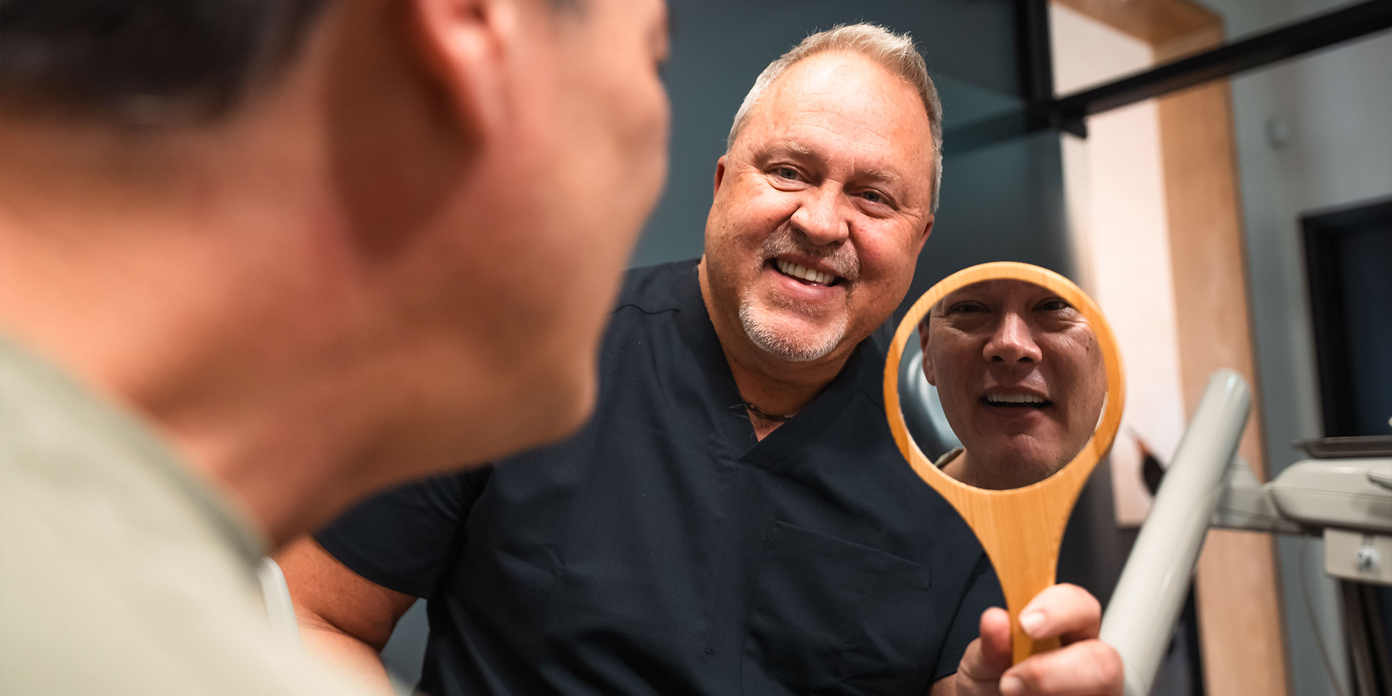 doctor showing patient there new smiles after full mouth dental implants
