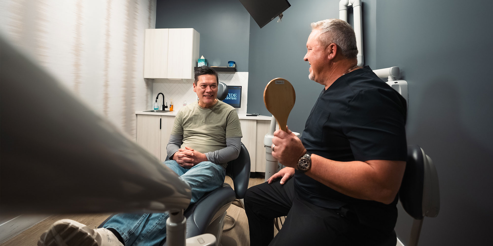 doctor showing patient there new smiles after dental implants